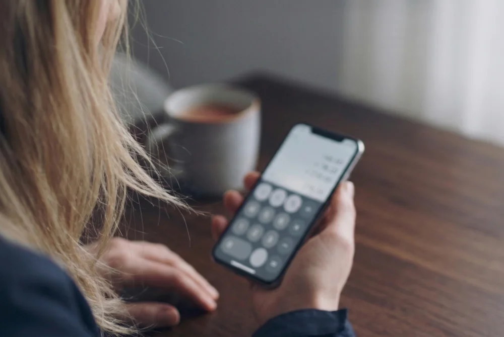 Kvinna räknar på kostnader i mobilen, kort skärpedjup.